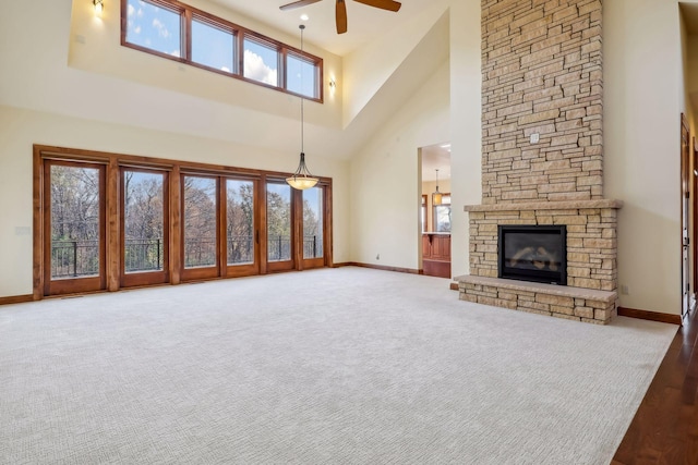 unfurnished living room with a fireplace, carpet, ceiling fan, and a high ceiling