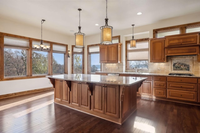 kitchen featuring backsplash, dark wood-type flooring, a center island, and a healthy amount of sunlight