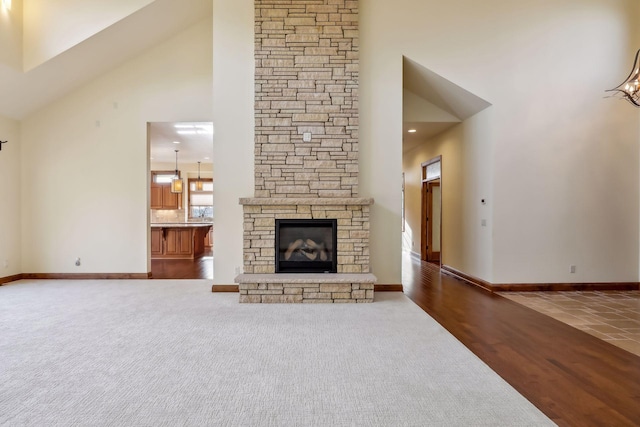 unfurnished living room with dark colored carpet, high vaulted ceiling, and a fireplace