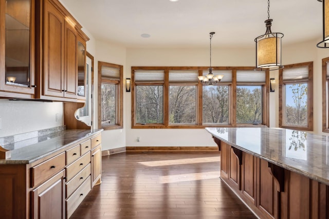 kitchen with dark hardwood / wood-style flooring, decorative light fixtures, dark stone counters, and an inviting chandelier