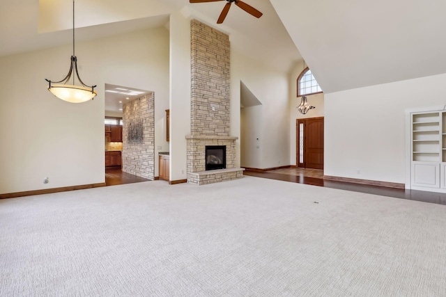 unfurnished living room with dark carpet, ceiling fan, a fireplace, and high vaulted ceiling