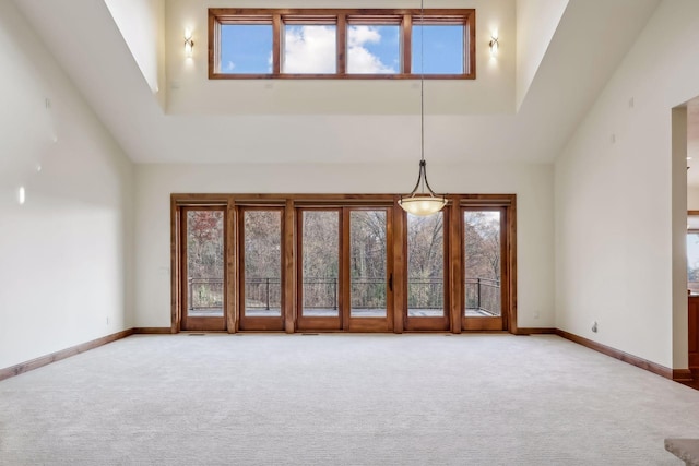 carpeted spare room featuring high vaulted ceiling and a healthy amount of sunlight