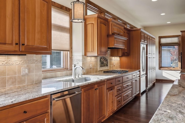 kitchen featuring light stone countertops, a wealth of natural light, stainless steel appliances, and sink