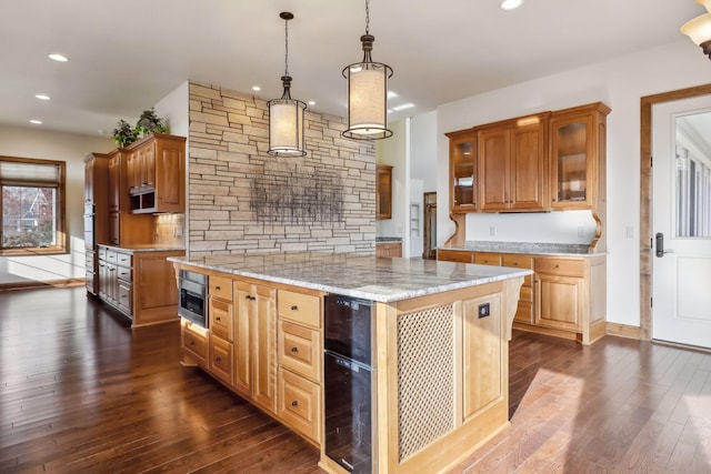 kitchen with wine cooler, dark wood-type flooring, a center island, hanging light fixtures, and light stone countertops