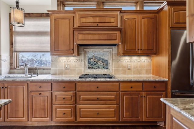 kitchen with sink, light stone counters, tasteful backsplash, hanging light fixtures, and appliances with stainless steel finishes