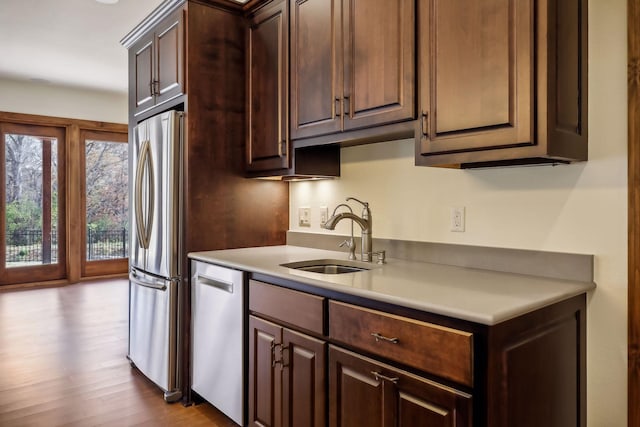 kitchen featuring stainless steel appliances, light hardwood / wood-style floors, sink, and dark brown cabinets