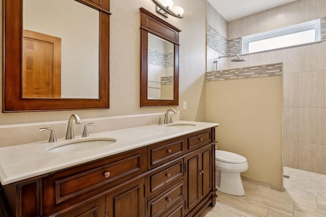 bathroom featuring vanity, a tile shower, and toilet