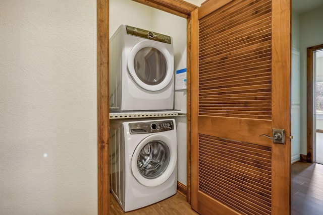 washroom with stacked washing maching and dryer and hardwood / wood-style floors