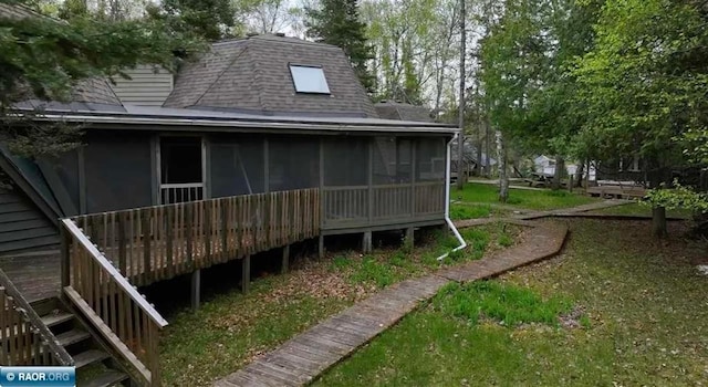 back of house featuring a sunroom and roof with shingles