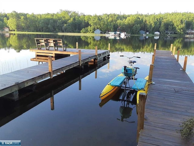 view of dock featuring a wooded view and a water view