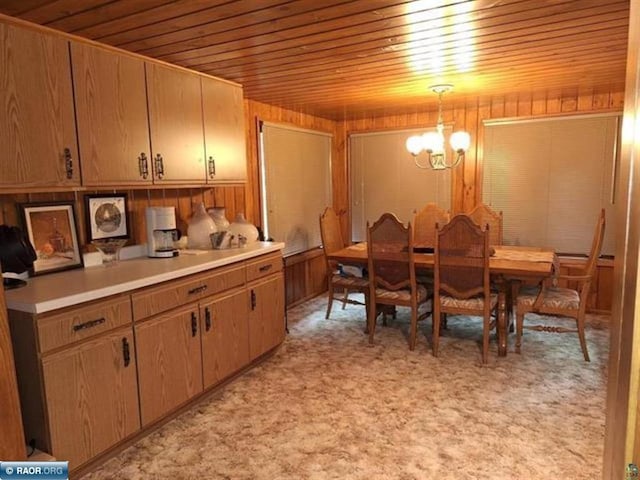 dining room featuring a notable chandelier, wood walls, light colored carpet, and wooden ceiling