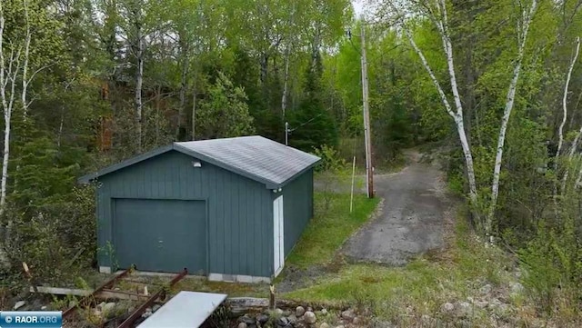 view of outdoor structure with a wooded view and an outbuilding