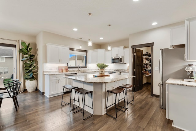 kitchen with pendant lighting, a center island, white cabinets, dark hardwood / wood-style floors, and stainless steel appliances