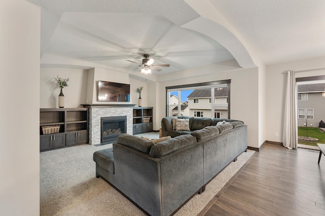 living room with a fireplace, ceiling fan, hardwood / wood-style floors, and a textured ceiling