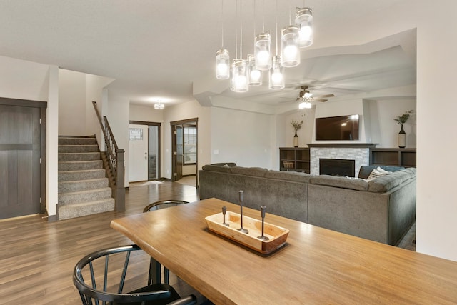 dining area featuring hardwood / wood-style floors, ceiling fan, and a stone fireplace