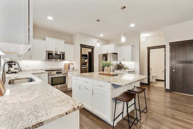 kitchen with dark hardwood / wood-style flooring, stainless steel appliances, white cabinetry, and sink