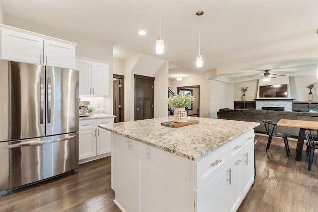 kitchen featuring stainless steel fridge, dark wood-type flooring, a center island, white cabinetry, and hanging light fixtures