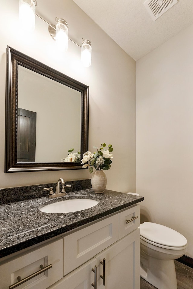 bathroom with vanity, toilet, wood-type flooring, and a textured ceiling