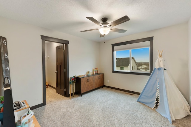 rec room featuring a textured ceiling, light colored carpet, and ceiling fan