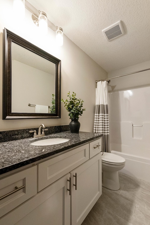 full bathroom featuring vanity, toilet, a textured ceiling, and shower / tub combo