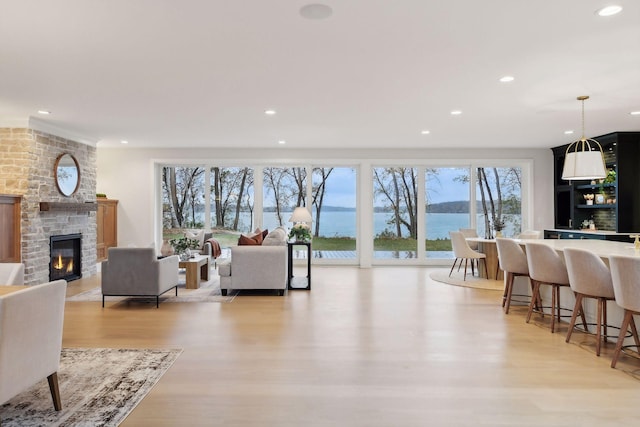 living room with a large fireplace, light hardwood / wood-style floors, and a water view