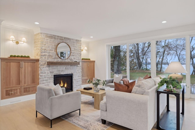 living room with ornamental molding, a wealth of natural light, light hardwood / wood-style floors, and a brick fireplace