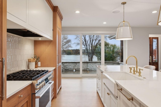 kitchen featuring plenty of natural light, tasteful backsplash, white cabinetry, and high end stove