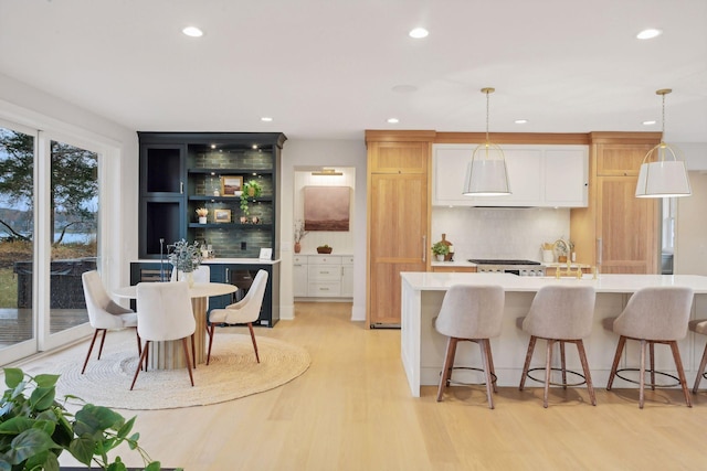 kitchen with tasteful backsplash, decorative light fixtures, and an island with sink