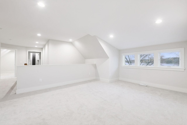 additional living space featuring light colored carpet and vaulted ceiling