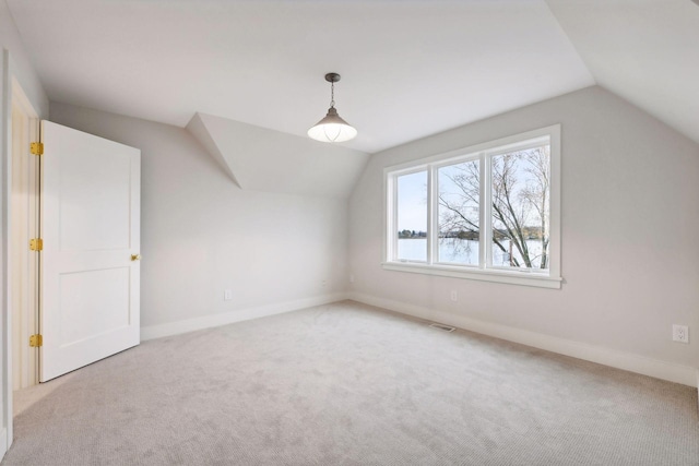 additional living space featuring light colored carpet and vaulted ceiling