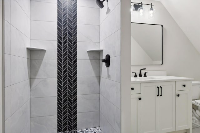 bathroom featuring vanity, vaulted ceiling, and tiled shower