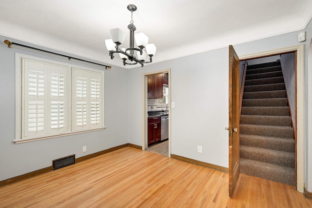 unfurnished room featuring a chandelier and light hardwood / wood-style floors