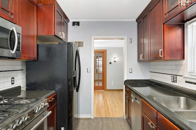 kitchen featuring sink, crown molding, tasteful backsplash, stainless steel appliances, and light hardwood / wood-style floors