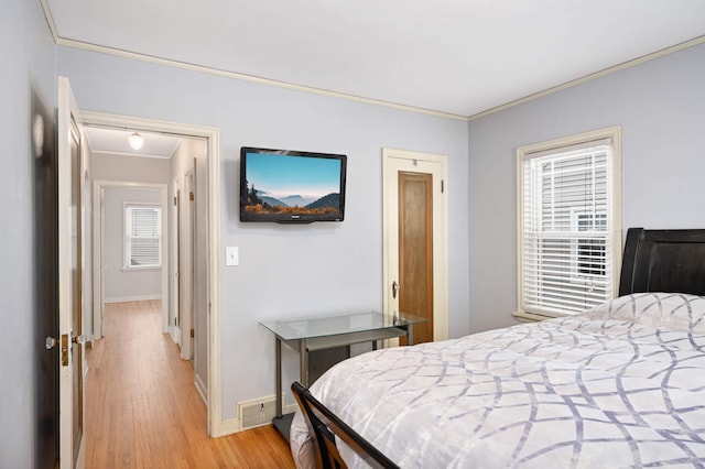 bedroom featuring ornamental molding, light hardwood / wood-style floors, and multiple windows