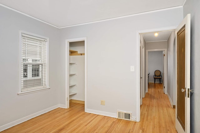 interior space featuring ornamental molding, a spacious closet, light hardwood / wood-style floors, and a closet