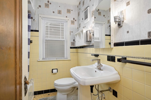 bathroom with toilet, sink, and tile walls