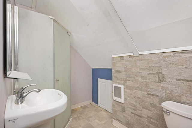 bathroom with lofted ceiling, sink, heating unit, and toilet