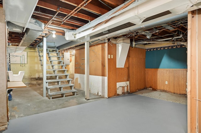 basement featuring wooden walls and electric panel