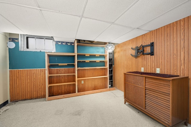 interior space featuring carpet floors, a paneled ceiling, and wooden walls