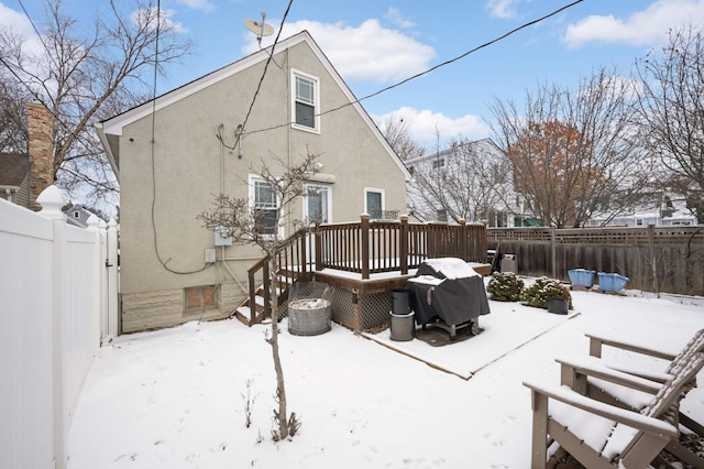 snow covered back of property with a wooden deck