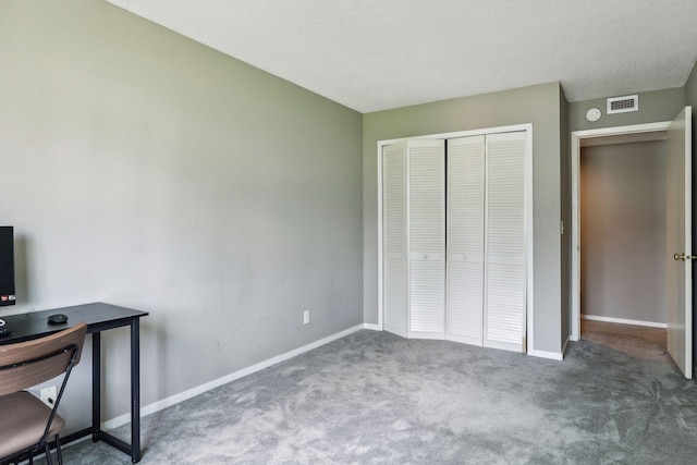 unfurnished bedroom with dark carpet, a textured ceiling, and a closet