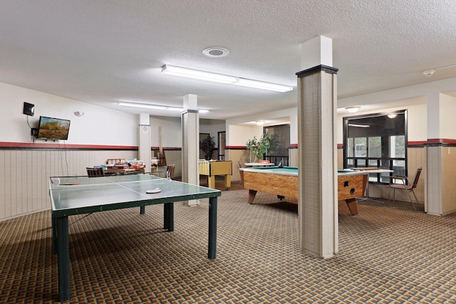 game room featuring billiards, carpet, a textured ceiling, ornate columns, and wooden walls