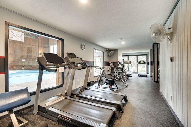 workout area with a textured ceiling and wooden walls