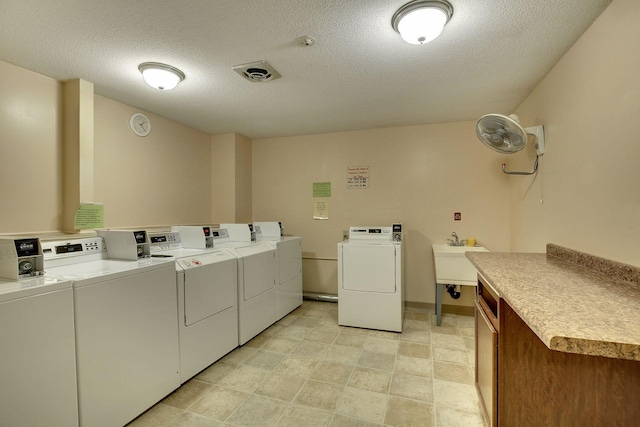 washroom featuring sink, a textured ceiling, and washer and clothes dryer