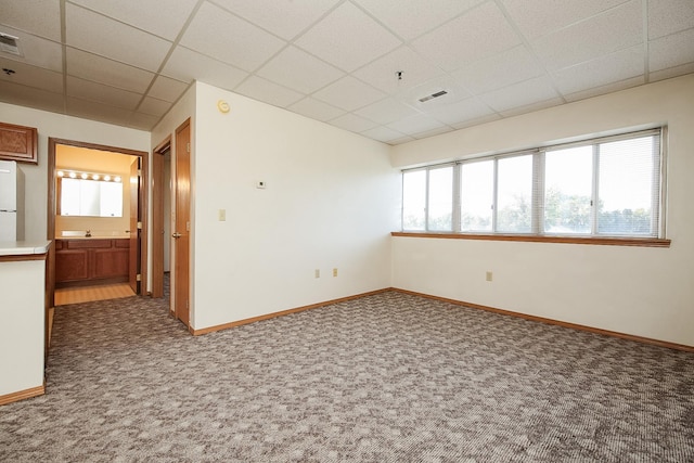 carpeted empty room featuring a paneled ceiling