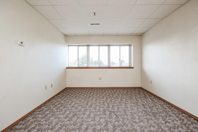 carpeted spare room featuring a drop ceiling