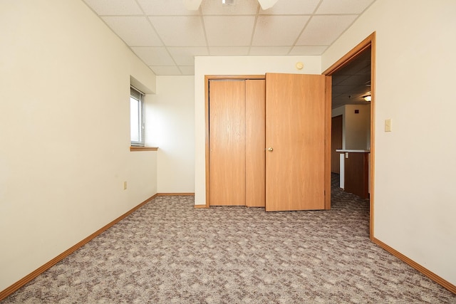 unfurnished bedroom featuring a closet, a paneled ceiling, ceiling fan, and carpet floors