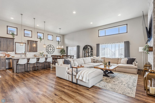 living room featuring sink, wood-type flooring, and a high ceiling