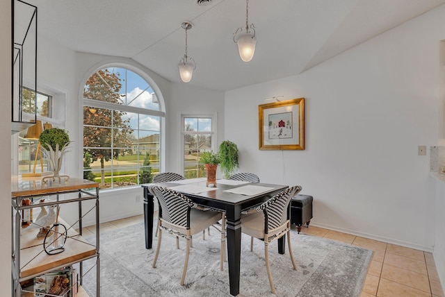 tiled dining space featuring vaulted ceiling