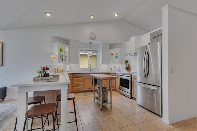 kitchen with sink, white cabinets, light tile patterned floors, stainless steel appliances, and wall chimney exhaust hood